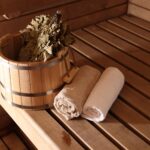 Bucket, whisk and towels on wooden bench in sauna