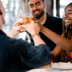 Group of diverse friends toasting with beer glasses while enjoying a meal together in a restaurant. Friends concept.
